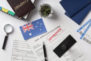 482 visa Australia application documents with approved visa form, Australian flag, passport, and boarding passes on the desk.
