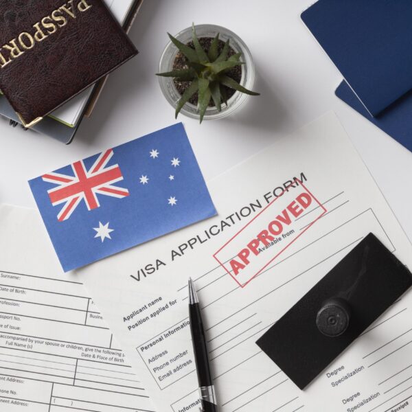 482 visa Australia application documents with approved visa form, Australian flag, passport, and boarding passes on the desk.