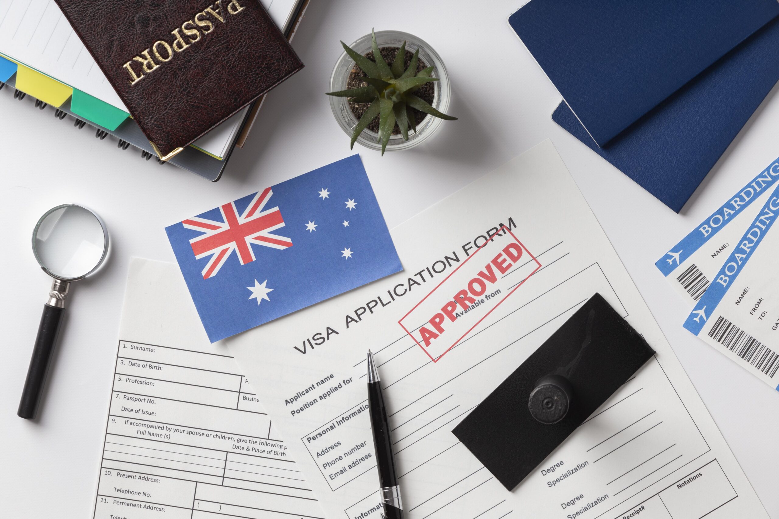482 visa Australia application documents with approved visa form, Australian flag, passport, and boarding passes on the desk.