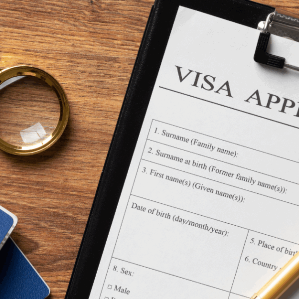 Australian PR visa application form with documents, magnifying glass and passport on wooden desk for immigration