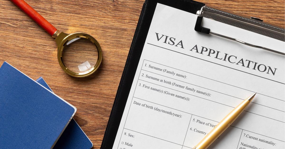 Australian PR visa application form with documents, magnifying glass and passport on wooden desk for immigration